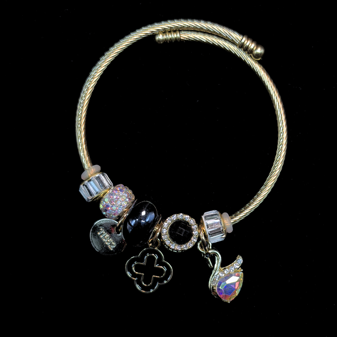 Charm Bracelet with various charms of an AD and iridescent stone swan, black bead, LV clover on a black background