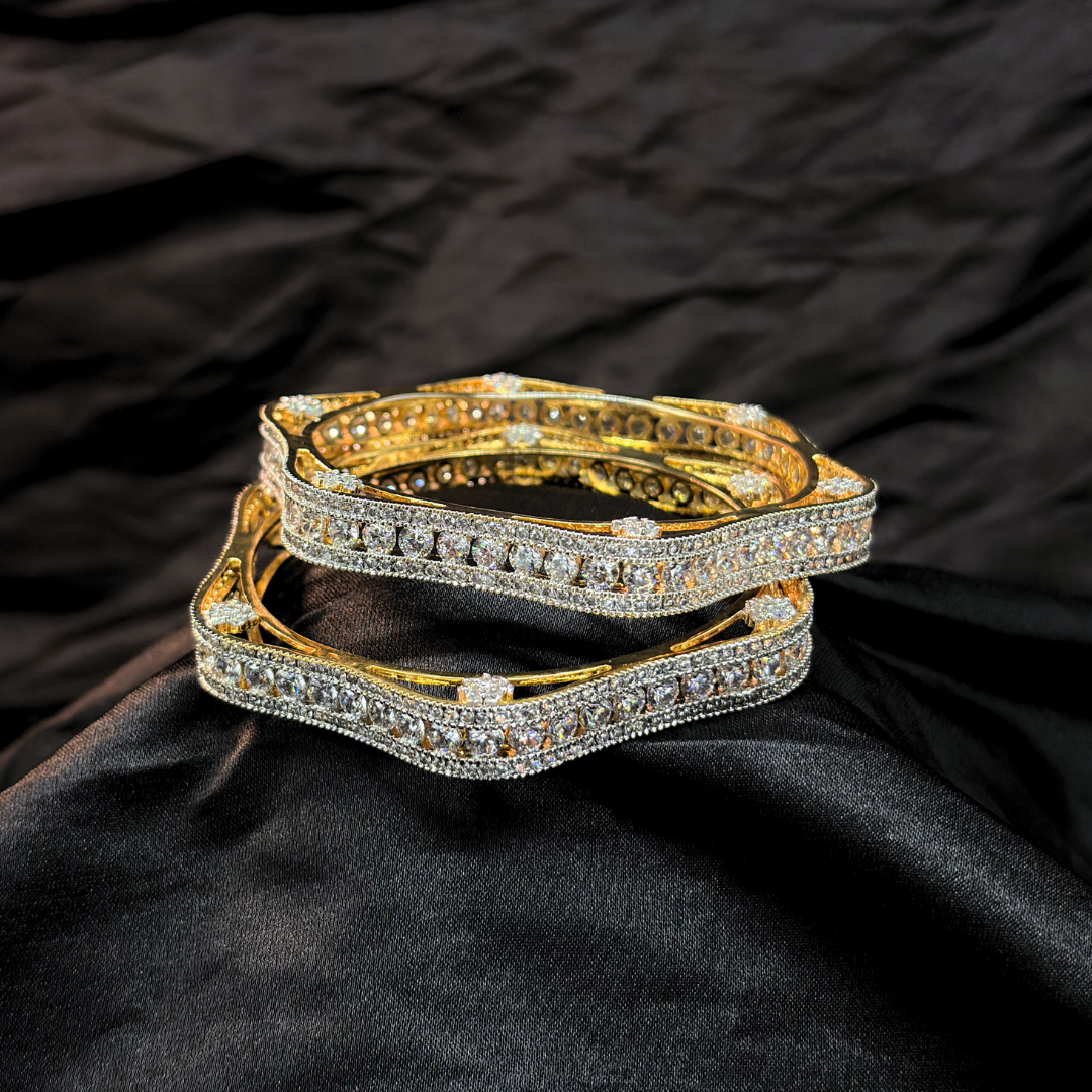 Two gold and diamond chudi/ bangles imitation jewellery that look like real on a black fabric background