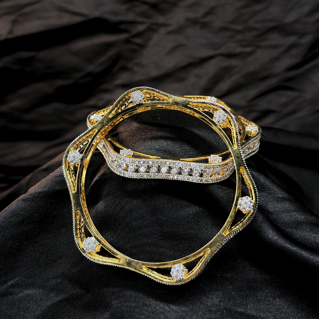 Two gold and diamond chudi/ bangles imitation jewellery that look like real on a black fabric background