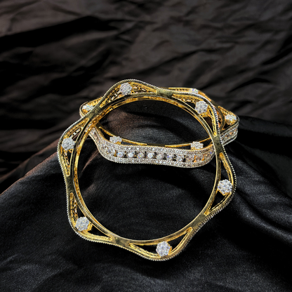 Two gold and diamond chudi/ bangles imitation jewellery that look like real on a black fabric background