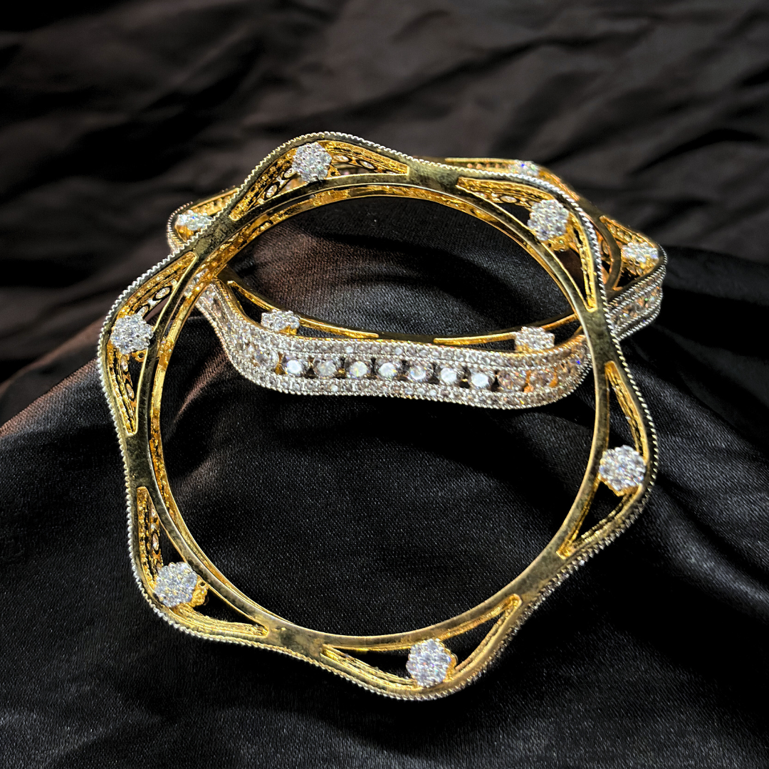Two gold and diamond chudi/ bangles imitation jewellery that look like real on a black fabric background