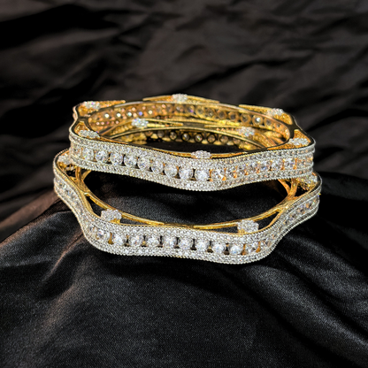 Two gold and diamond chudi/ bangles imitation jewellery that look like real on a black fabric background