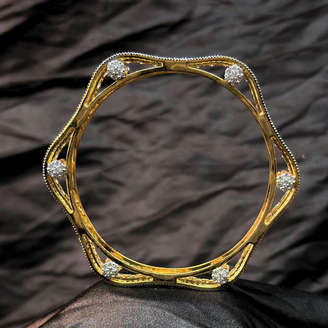 Two gold and diamond chudi/ bangles imitation jewellery that look like real on a black fabric background
