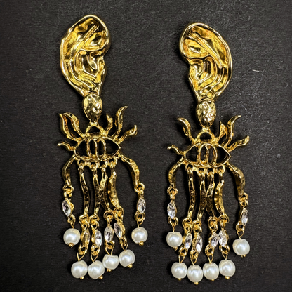 Gold and pearl schiaparelli inspired earrings on a black background