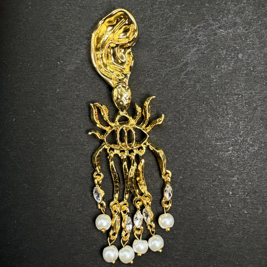 Gold and pearl schiaparelli inspired earrings on a black background