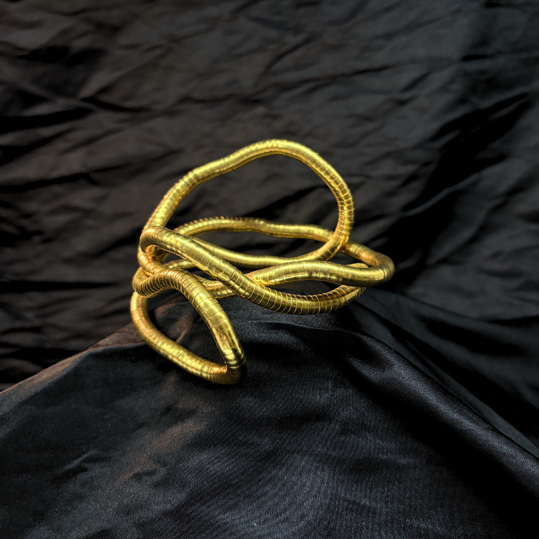 Trendy Gold mouldable necklace and bracelet with a textured design on a black textured fabric background