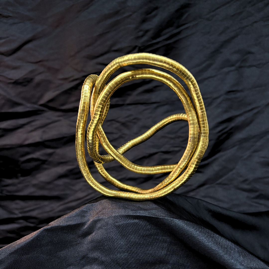 Trendy Gold mouldable necklace and bracelet with a textured design on a black textured fabric background
