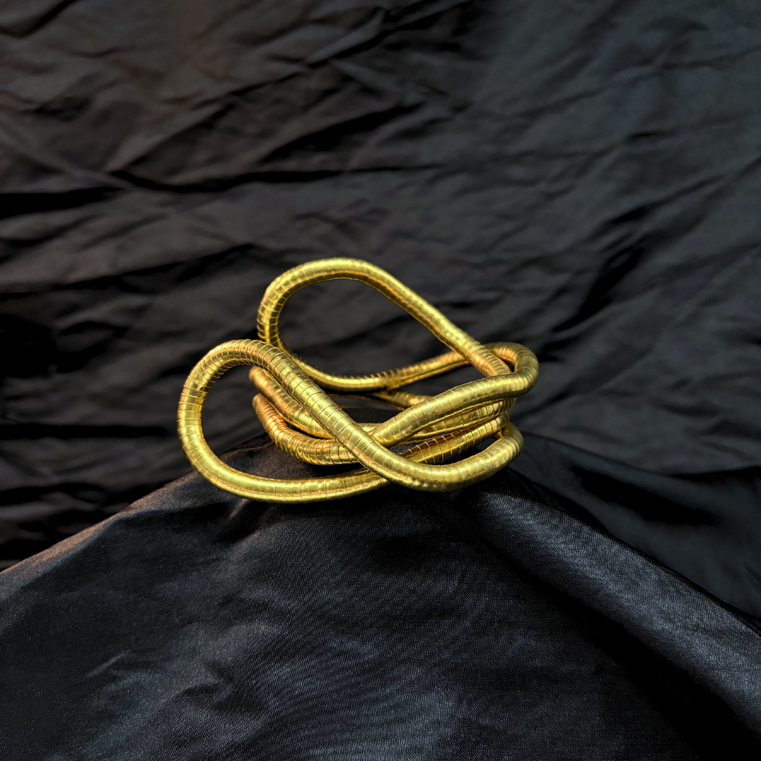 Trendy Gold mouldable necklace and bracelet with a textured design on a black textured fabric background