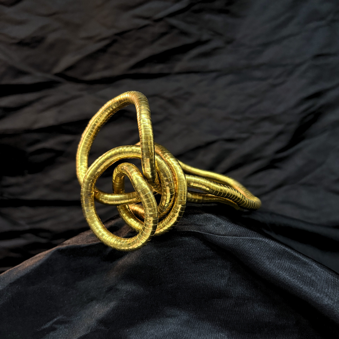 Trendy Gold mouldable necklace and bracelet with a textured design on a black textured fabric background