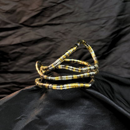 Trendy Gold, silver and black mouldable necklace and bracelet with a textured design on a black textured fabric background