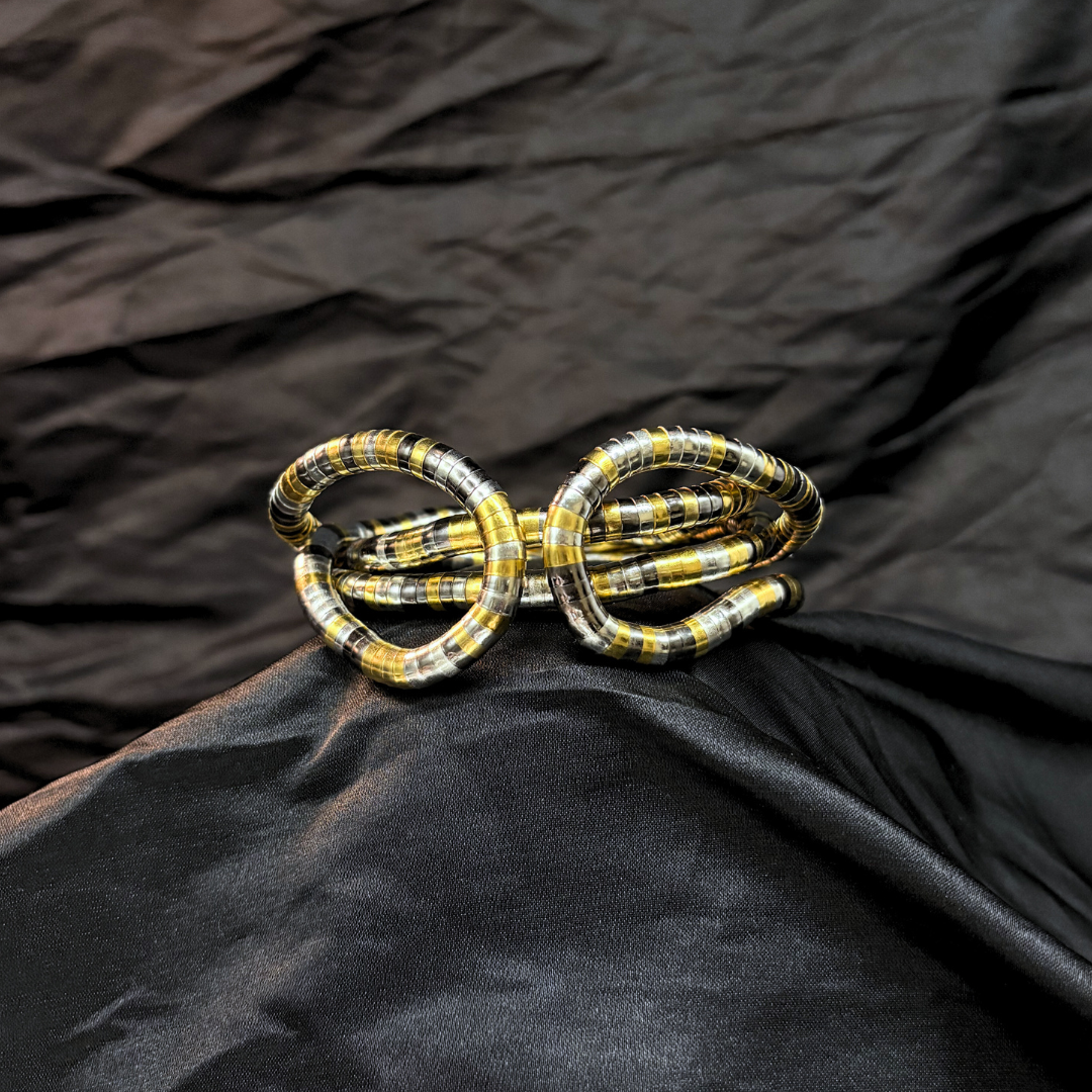 Trendy Gold, silver and black mouldable necklace and bracelet with a textured design on a black textured fabric background