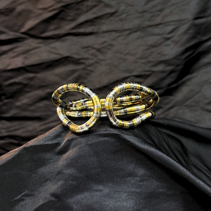 Trendy Gold, silver and black mouldable necklace and bracelet with a textured design on a black textured fabric background