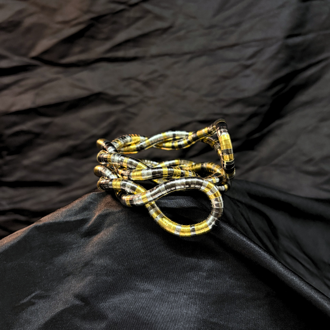 Trendy Gold, silver and black mouldable necklace and bracelet with a textured design on a black textured fabric background