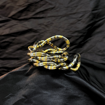 Trendy Gold, silver and black mouldable necklace and bracelet with a textured design on a black textured fabric background