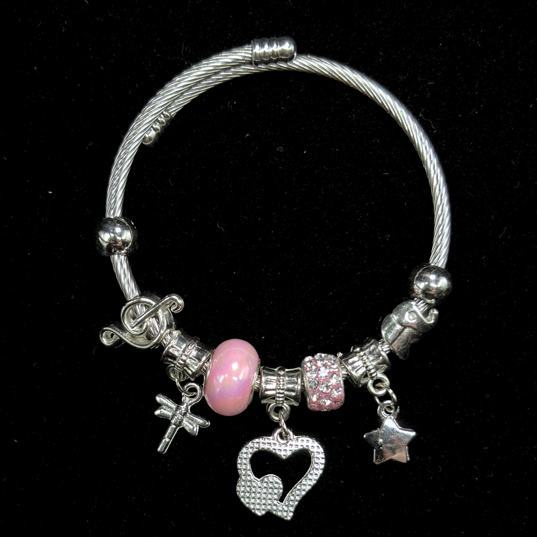 Bracelet with various charms including a pink bead, hearts, music notes, dragon fly  and star on a black background