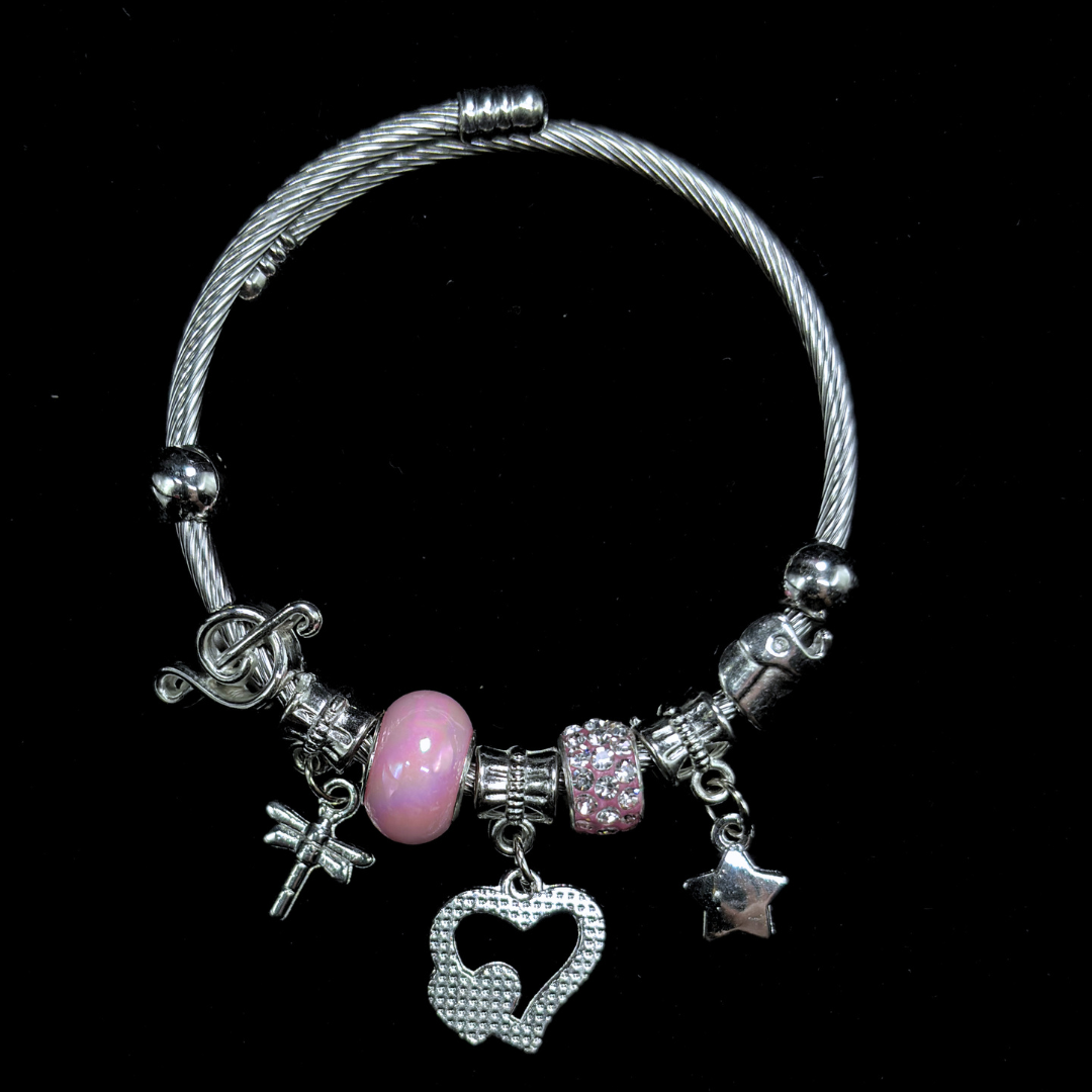 Bracelet with various charms including a pink bead, hearts, music notes, dragon fly  and star on a black background