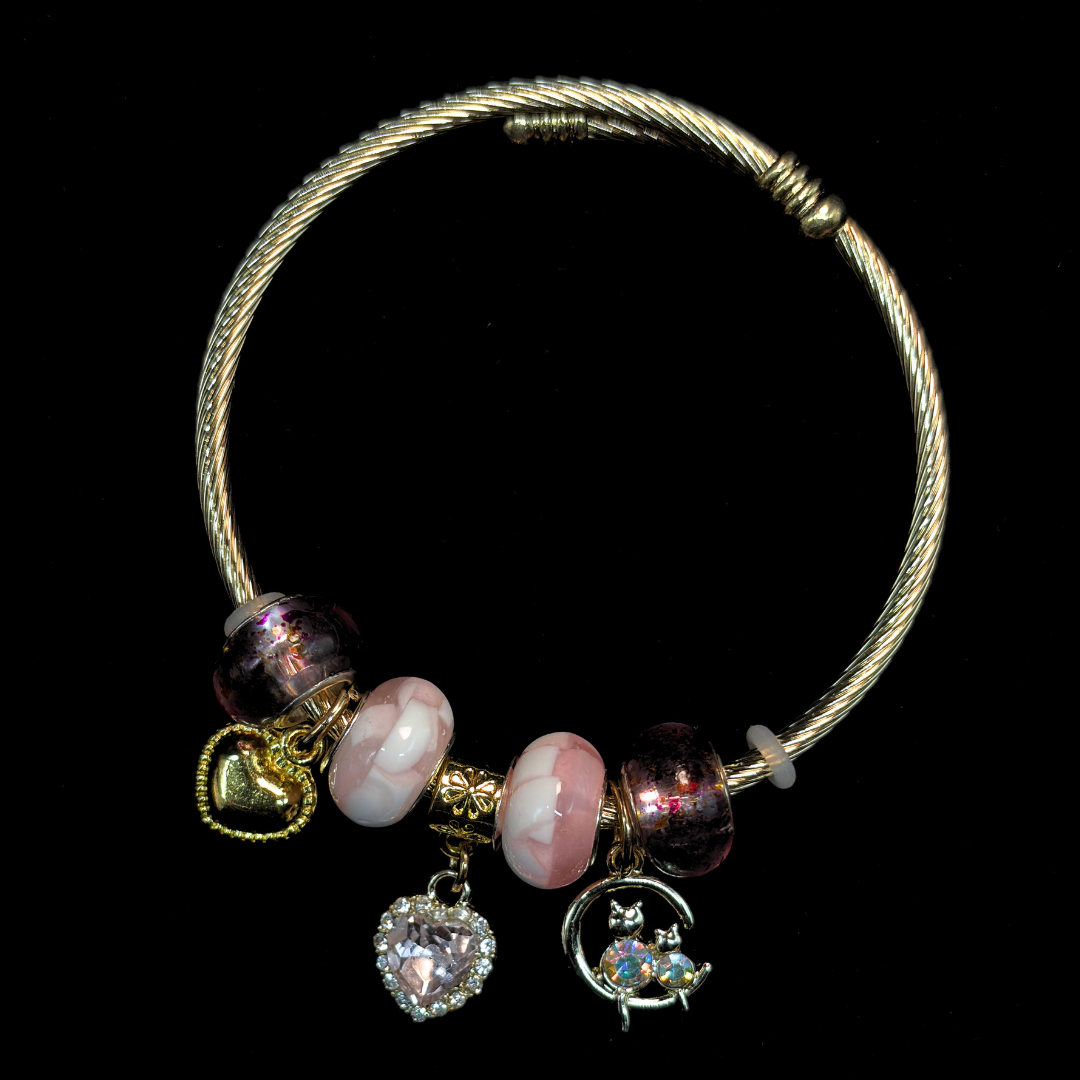 Charm Bracelet with pink and white marble beads and charms of iridescent stone cats, AD heart, hearts and glass beads on a black background