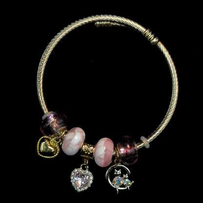 Charm Bracelet with pink and white marble beads and charms of iridescent stone cats, AD heart, hearts and glass beads on a black background