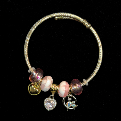 Charm Bracelet with pink and white marble beads and charms of iridescent stone cats, AD heart, hearts and glass beads on a black background