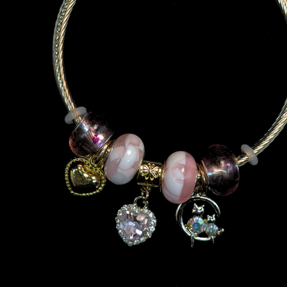 Charm Bracelet with pink and white marble beads and charms of iridescent stone cats, AD heart, hearts and glass beads on a black background