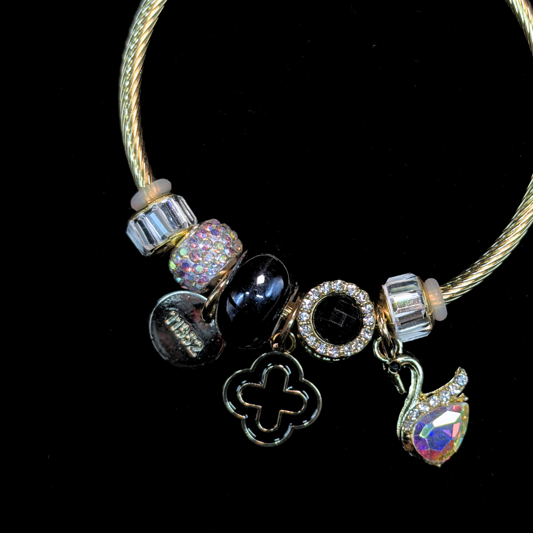 Charm Bracelet with various charms of an AD and iridescent stone swan, black bead, LV clover  on a black background