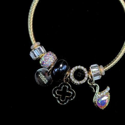 Charm Bracelet with various charms of an AD and iridescent stone swan, black bead, LV clover  on a black background